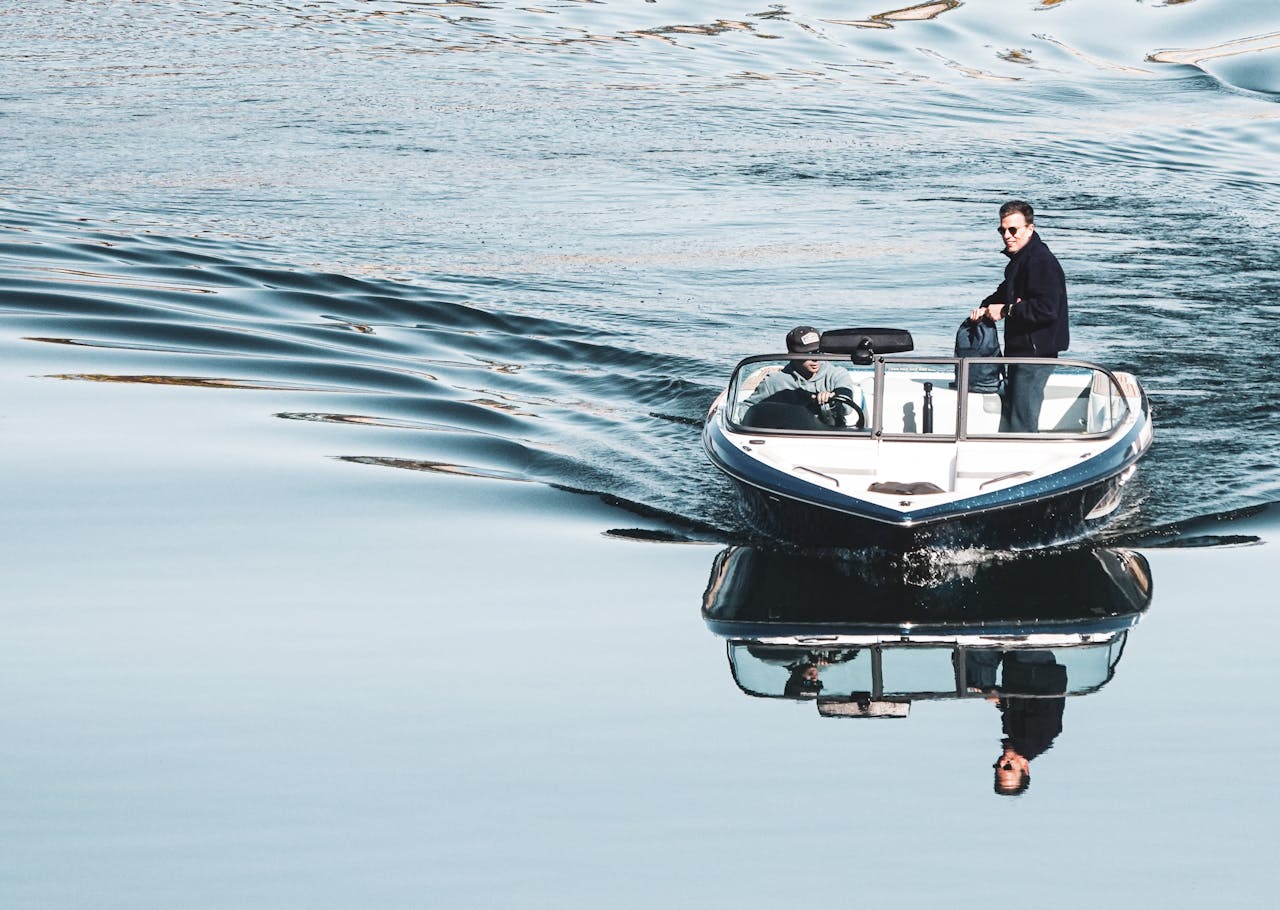 Two men on a speedboat creating reflections on a serene ocean. Perfect for travel and adventure themes.