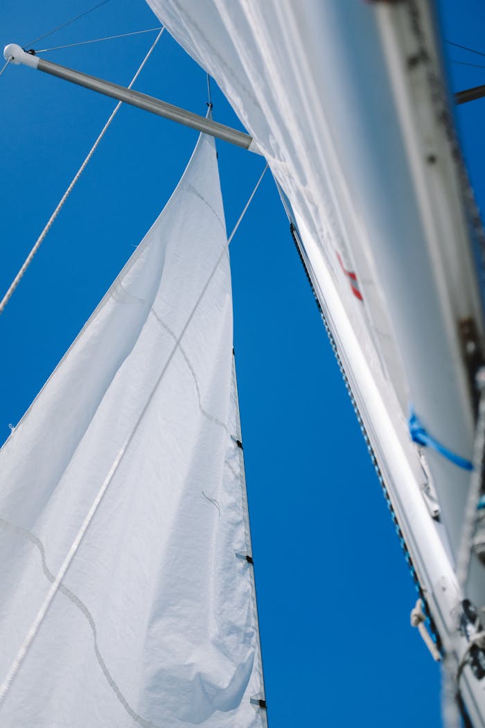 Close-up view of a sailboat mast and rigging against a clear blue sky, captured outdoors.